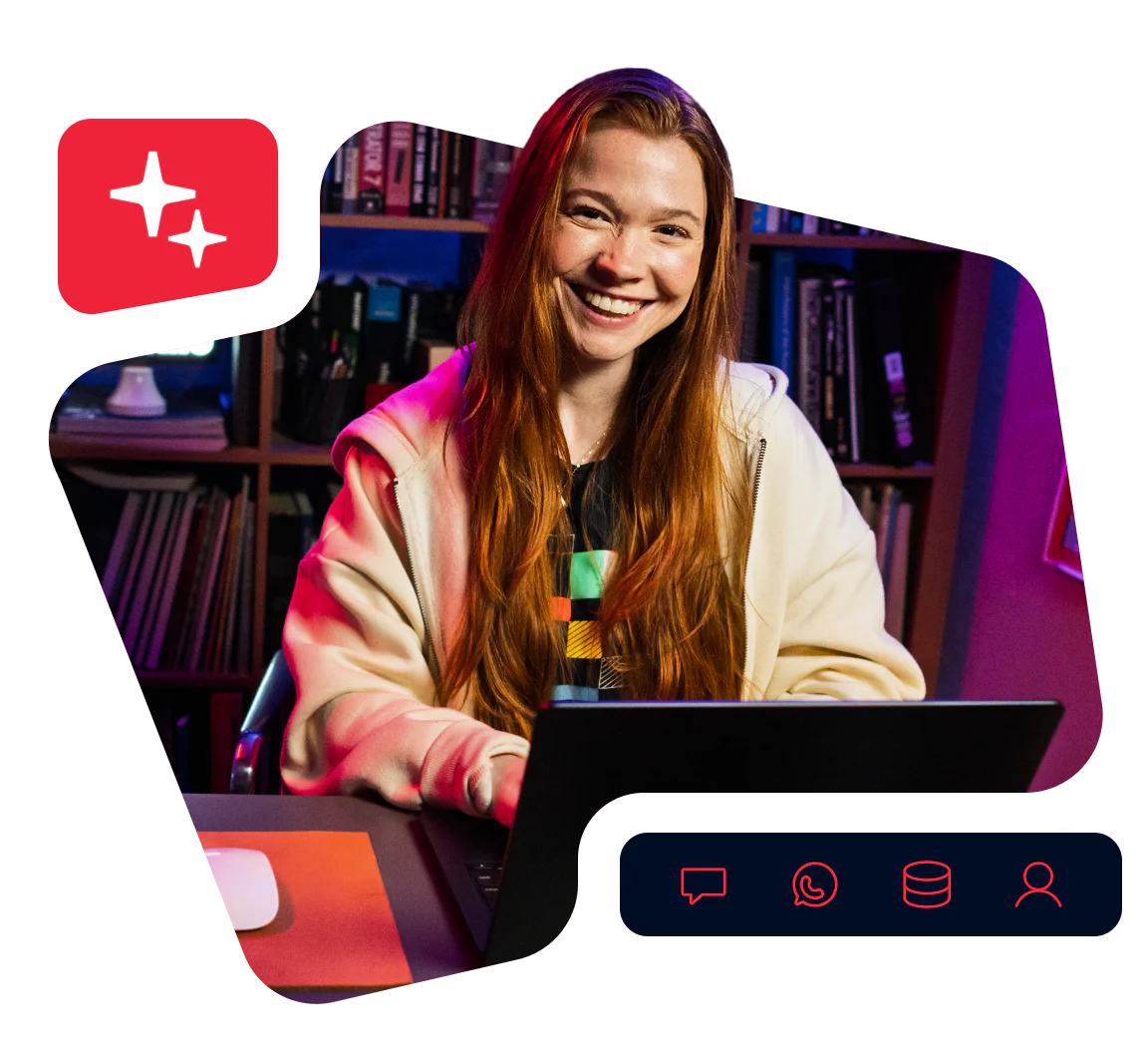 Woman with long red hair smiling and using a laptop in a cozy room with bookshelves.