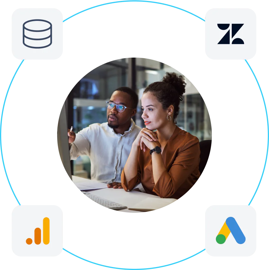 Two coworkers reviewing a computer screen in an office, surrounded by icons for a database, Zendesk, Google Analytics, and Google Ads, suggesting data integration.