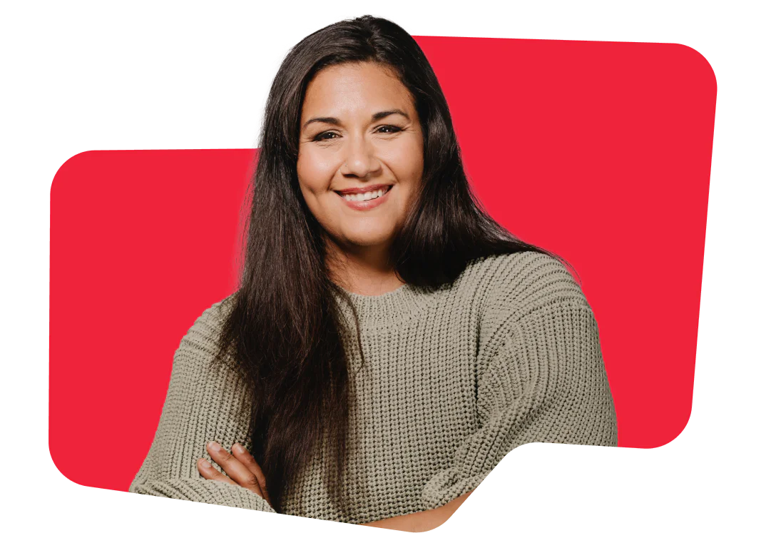 Smiling woman with long dark hair, wearing a beige sweater, in front of a red background