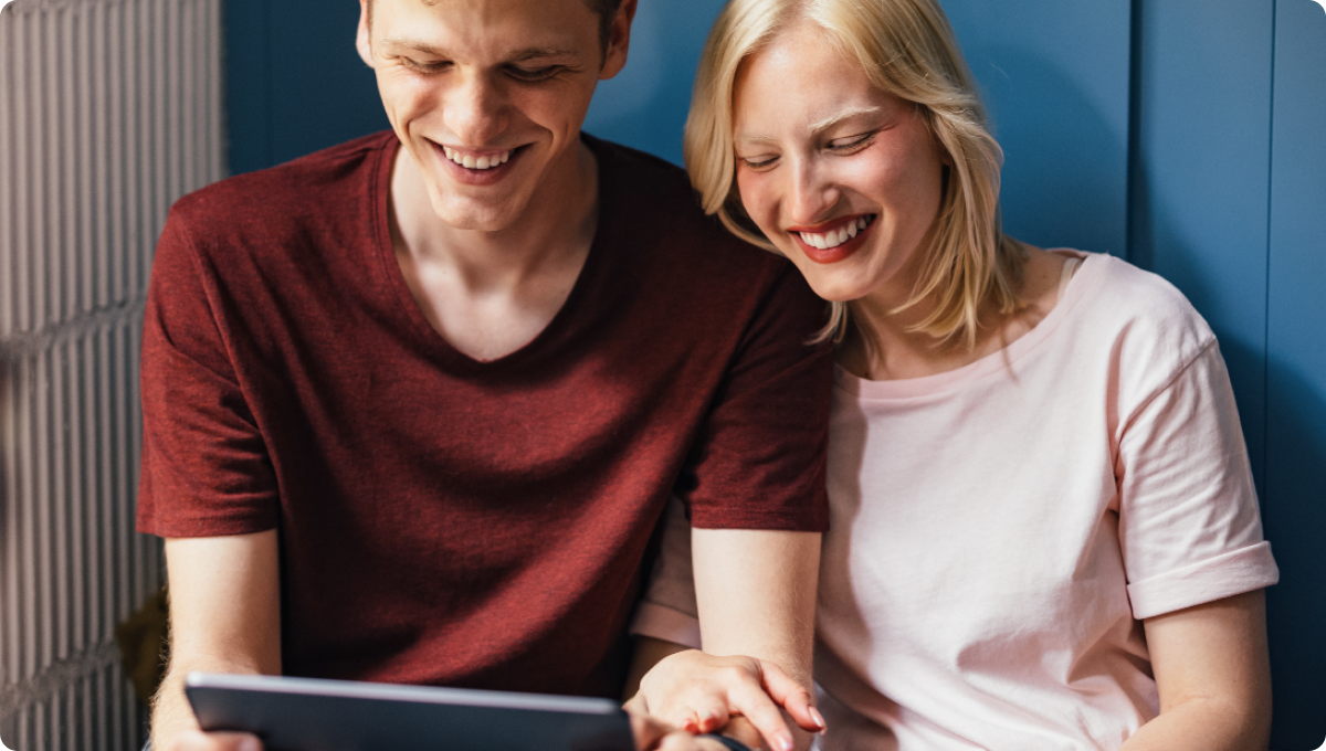 Two people looking at a tablet and smiling