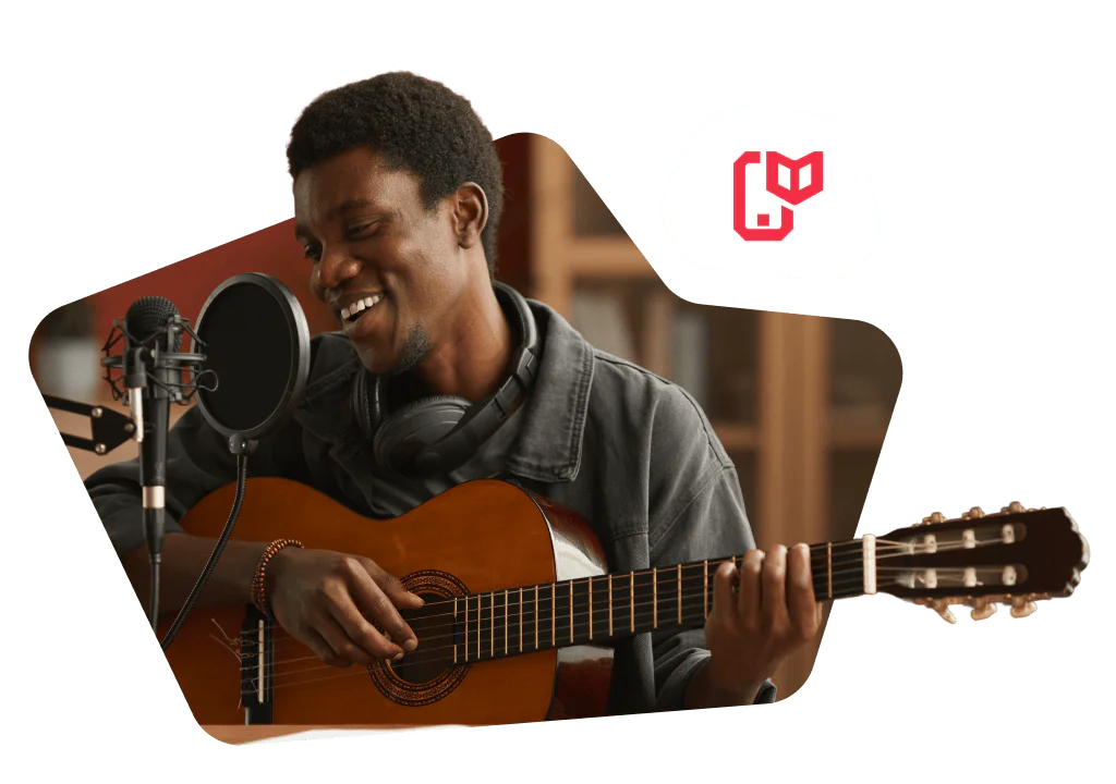 Man playing guitar and singing into a microphone with headphones around his neck.