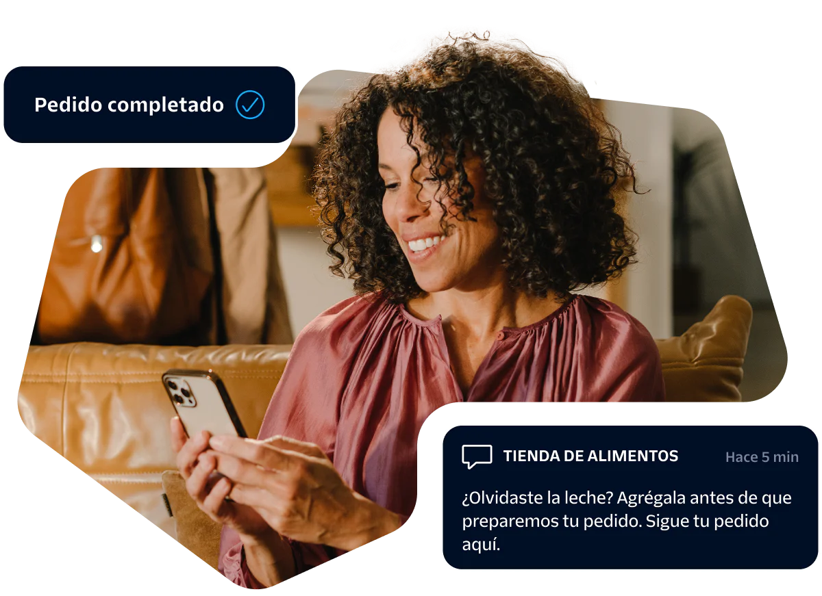 Woman smiling at her smartphone while receiving an online grocery order confirmation message.