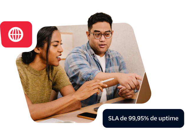 Two colleagues discussing work at a laptop showcasing a commitment to 99.95% uptime SLA