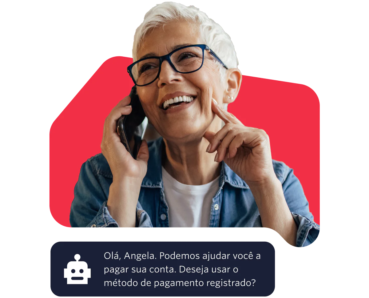 Elderly woman with glasses smiling while talking on the phone against a red background.