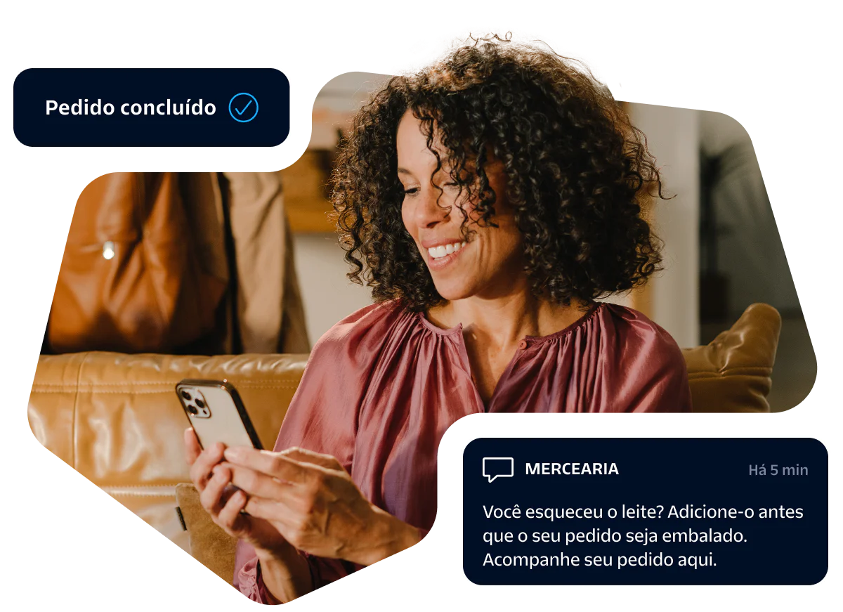 Woman smiling at her smartphone while receiving an online grocery order confirmation message.