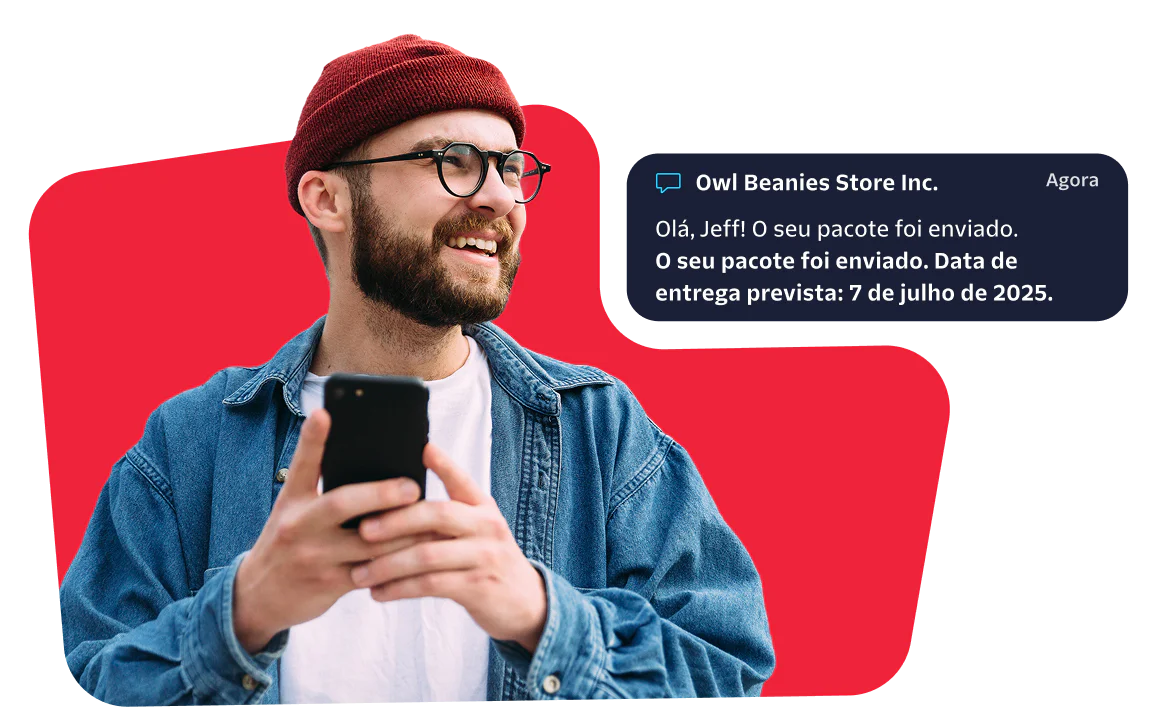 Smiling man with a red beanie checks his phone for a message about his package delivery.
