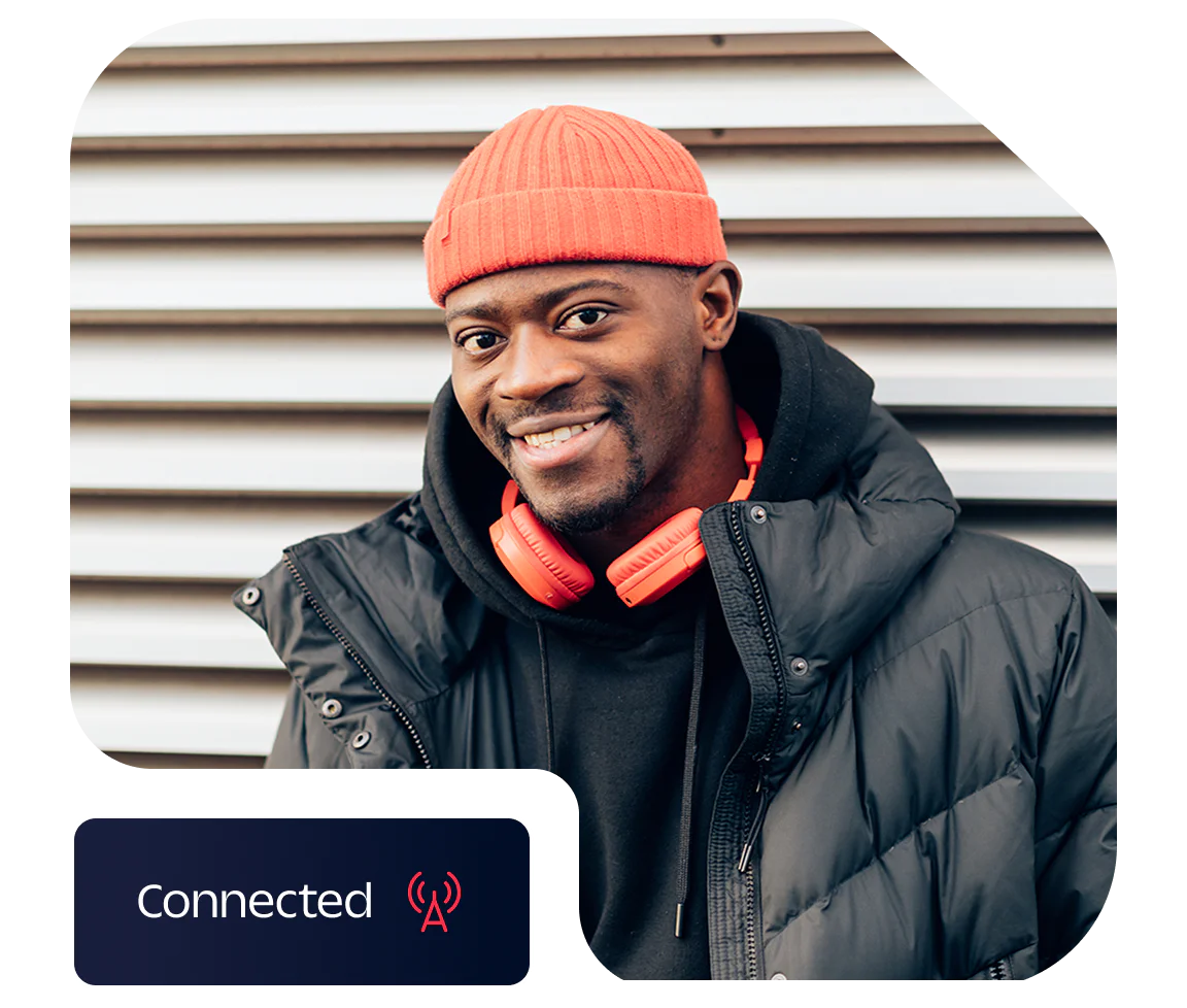 Smiling Man Wearing Red Beanie and Headphones Man in red beanie and orange headphones smiling in front of striped wall